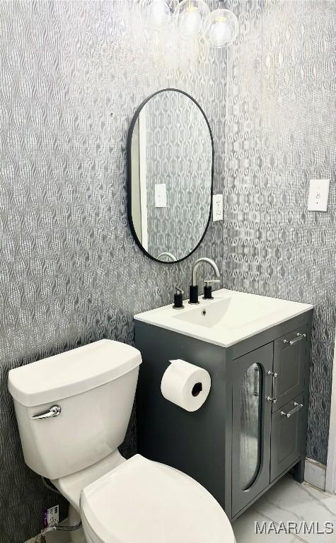 644 Iris Ln, Montgomery, AL 36105 - half bathroom featuring toilet, wallpapered walls, vanity, and marble look tiles