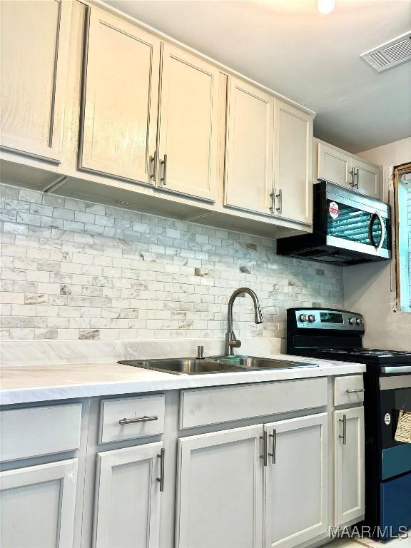 644 Iris Ln, Montgomery, AL 36105 - kitchen with range with electric cooktop, stainless steel microwave, a sink, decorative backsplash, and light countertops