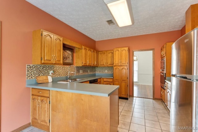 kitchen featuring decorative backsplash, a sink, visible vents, stainless steel appliances, and a peninsula
