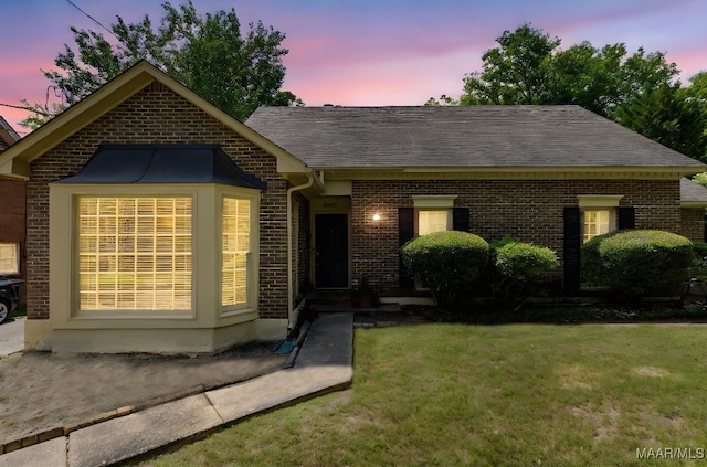 ranch-style home with a front lawn, a shingled roof, and brick siding