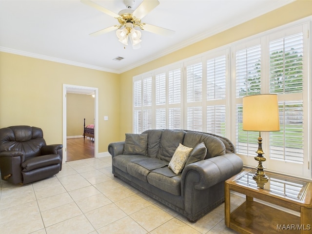 living area featuring light tile patterned flooring, visible vents, a ceiling fan, and ornamental molding