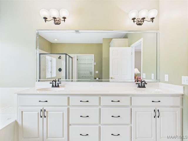 bathroom featuring double vanity, a bath, a stall shower, and a sink