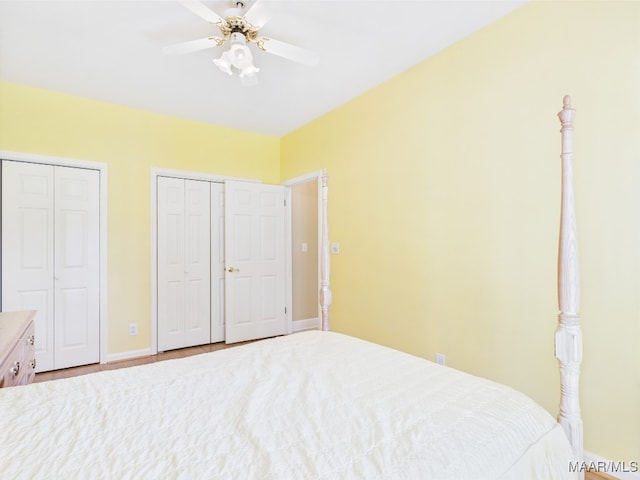bedroom with a ceiling fan, two closets, and baseboards
