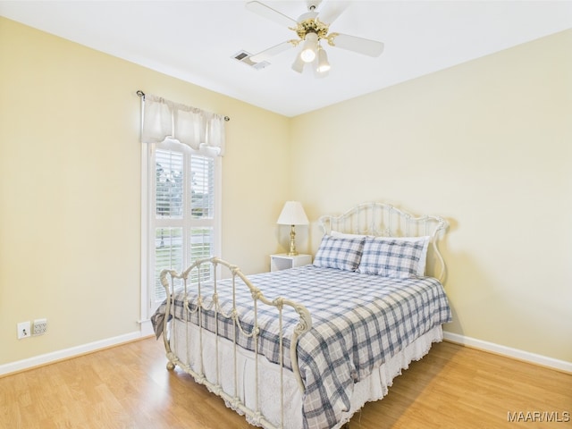 bedroom with baseboards, visible vents, wood finished floors, and a ceiling fan