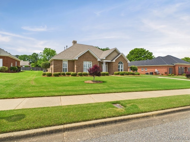single story home featuring fence, a chimney, brick siding, and a front lawn