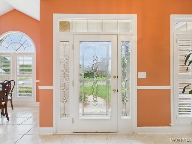 foyer entrance with baseboards, light tile patterned floors, and vaulted ceiling