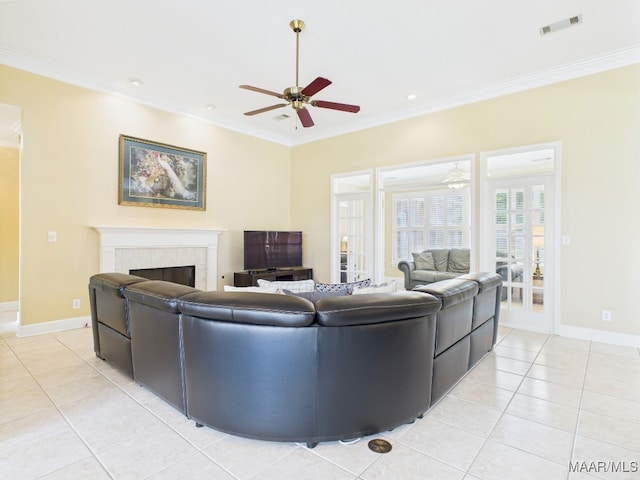 living room with light tile patterned floors, a tiled fireplace, a ceiling fan, and crown molding