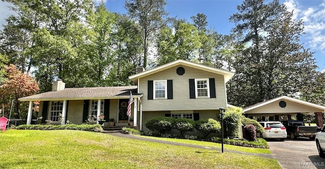 split level home with a porch, a front lawn, driveway, a detached carport, and a chimney