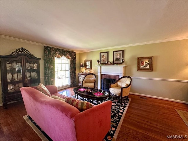 living room with baseboards, wood finished floors, ornamental molding, and a fireplace