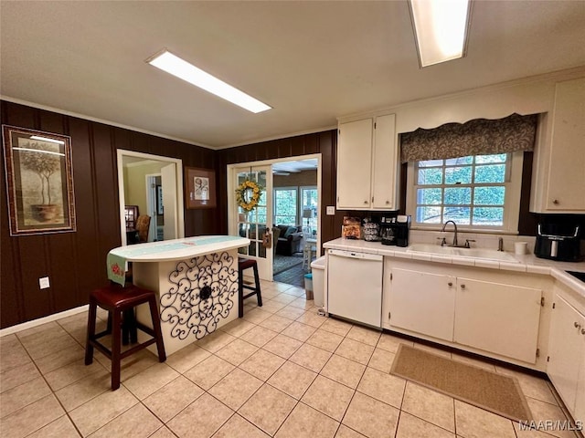 kitchen with light tile patterned floors, white cabinetry, plenty of natural light, and white dishwasher