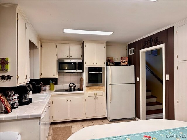 kitchen with tasteful backsplash, stainless steel appliances, light tile patterned floors, visible vents, and tile countertops