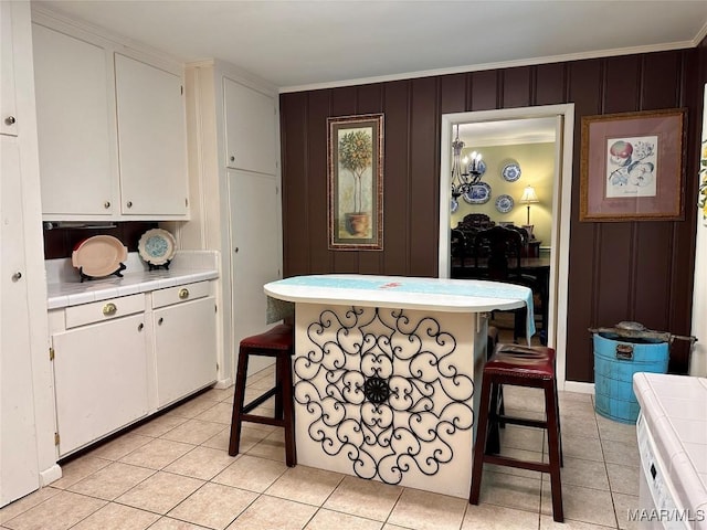 kitchen with a breakfast bar, white cabinets, light tile patterned floors, and tile counters
