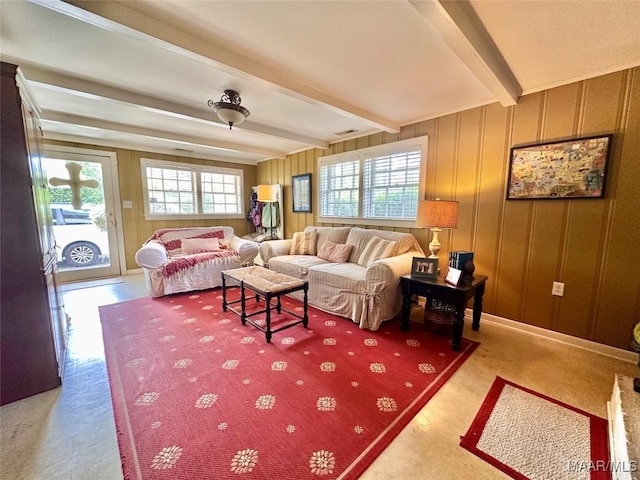 living area with beam ceiling, visible vents, and a decorative wall