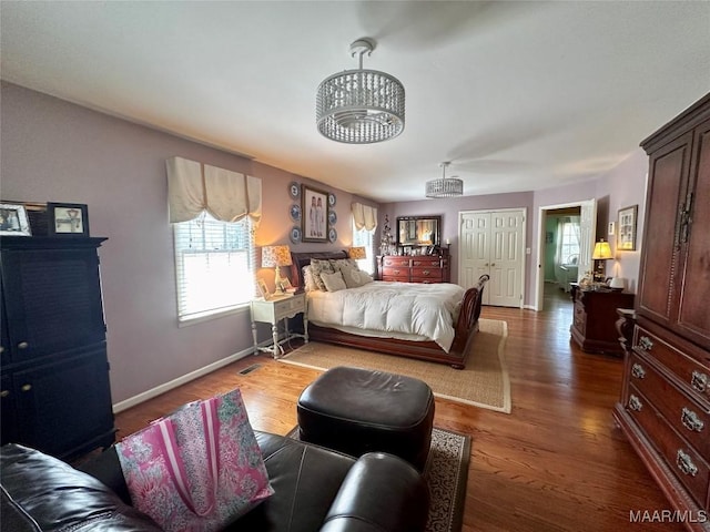 bedroom featuring visible vents, wood finished floors, a notable chandelier, and baseboards