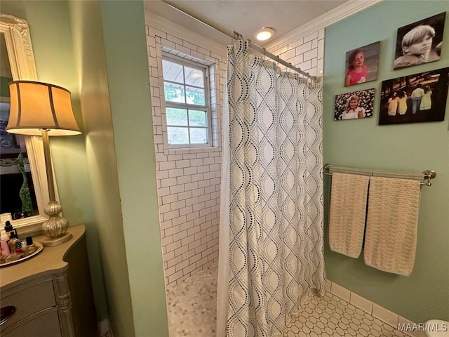 bathroom featuring ornamental molding, a tile shower, vanity, and baseboards