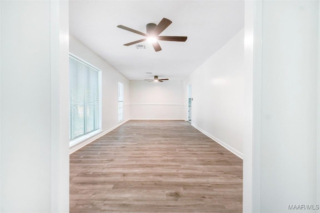 hallway featuring baseboards, visible vents, and wood finished floors