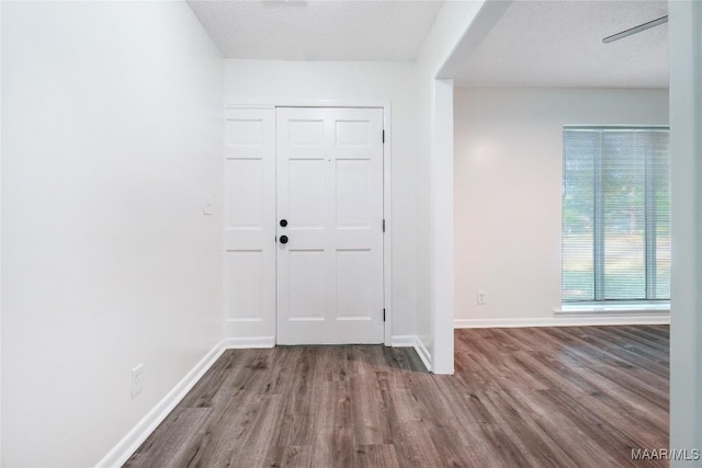 entryway with baseboards, wood finished floors, and a textured ceiling