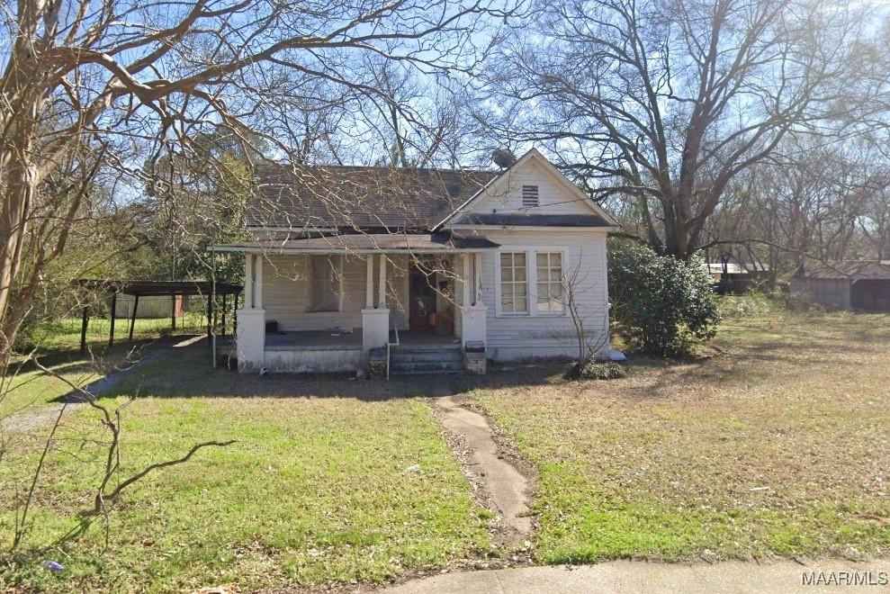 view of front facade featuring covered porch, a detached carport, and a front lawn