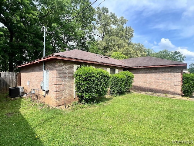 view of home's exterior featuring cooling unit, a lawn, fence, and brick siding