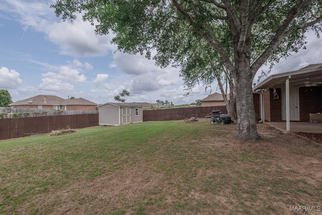 view of yard with a fenced backyard, an outdoor structure, a storage unit, ceiling fan, and a patio area
