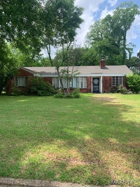 single story home with a front lawn, brick siding, and a chimney