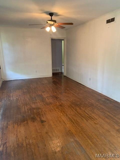 spare room with dark wood-style floors, a ceiling fan, and visible vents