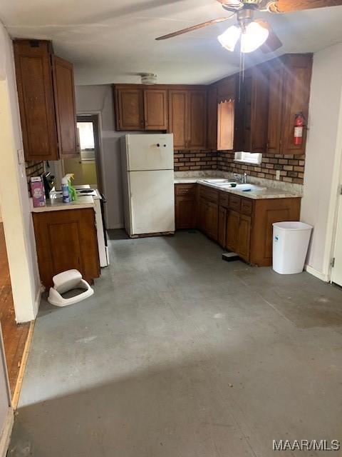kitchen with a ceiling fan, finished concrete flooring, brown cabinetry, and white appliances