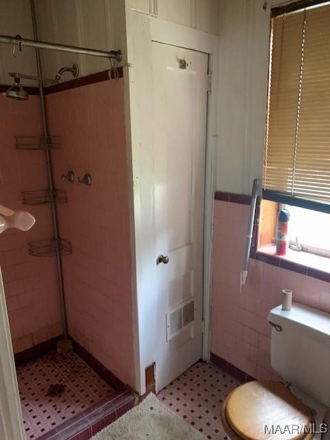 bathroom with tile walls, a shower stall, tile patterned floors, toilet, and visible vents