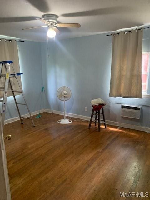 unfurnished bedroom with baseboards, wood finished floors, and a wall mounted AC