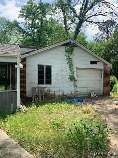 view of side of property featuring a detached garage, driveway, and a shingled roof