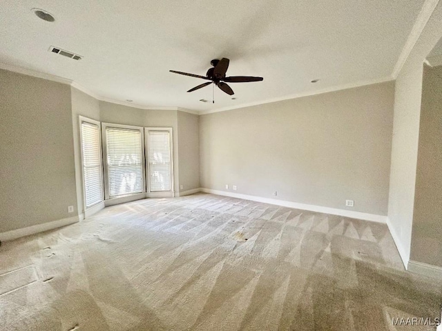 empty room with light colored carpet, ornamental molding, baseboards, visible vents, and a ceiling fan