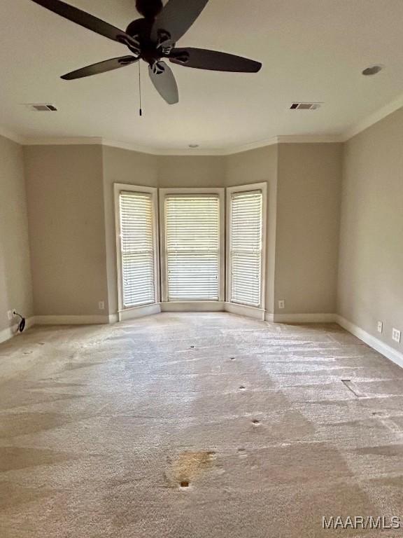 empty room featuring ornamental molding, carpet flooring, a wealth of natural light, and visible vents