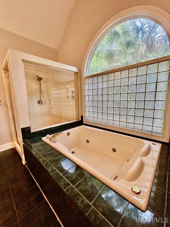 bathroom with tile patterned floors and a tub with jets