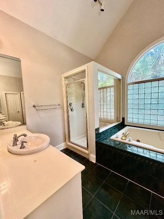 full bath featuring a shower stall, vaulted ceiling, a garden tub, vanity, and tile patterned flooring