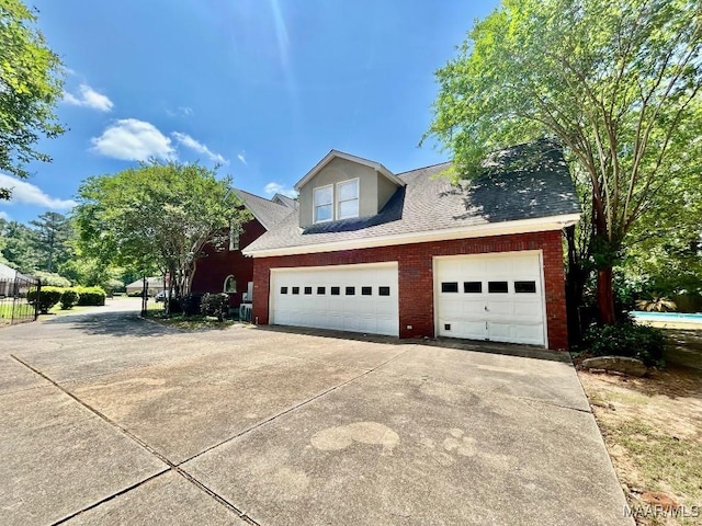 view of property exterior featuring driveway, a shingled roof, and brick siding