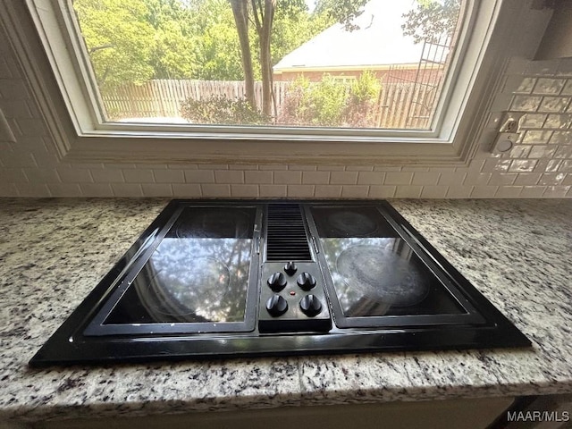 room details featuring light stone countertops, black electric stovetop, and tasteful backsplash