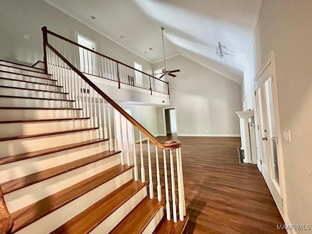stairs with wood finished floors, ornamental molding, ceiling fan, baseboards, and lofted ceiling