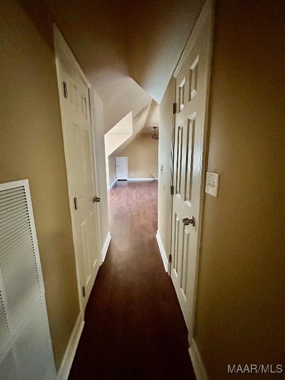 hall with baseboards, wood finished floors, lofted ceiling, and a heating unit