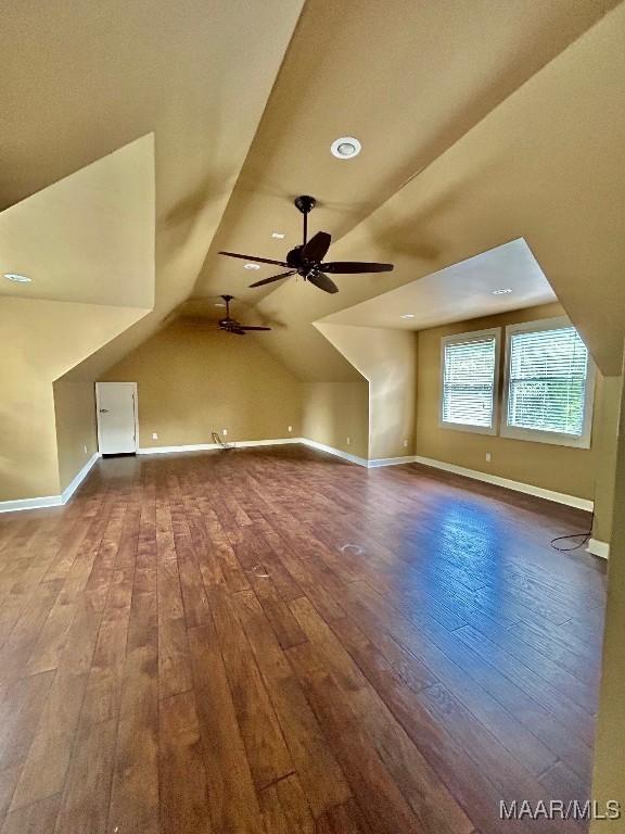 bonus room featuring dark wood-style floors, a ceiling fan, vaulted ceiling, and baseboards
