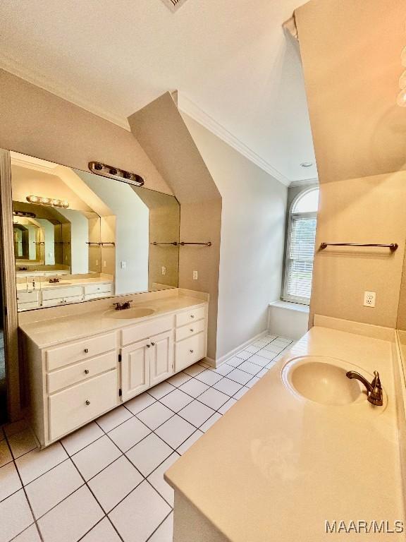 bathroom with vaulted ceiling, two vanities, tile patterned flooring, and a sink