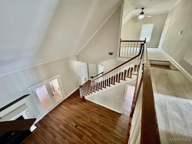 stairs featuring wood finished floors, a ceiling fan, vaulted ceiling, and baseboards