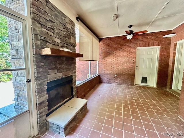 interior space with a stone fireplace, ceiling fan, and tile patterned flooring