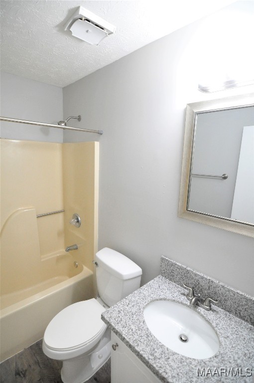 bathroom featuring vanity, bathing tub / shower combination, toilet, a textured ceiling, and wood finished floors