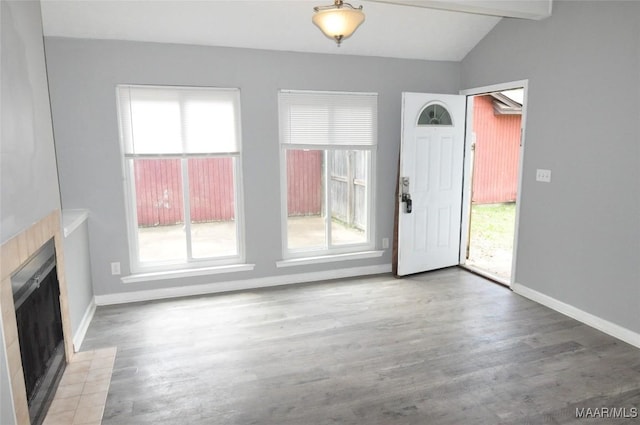 unfurnished living room with a fireplace, wood finished floors, lofted ceiling with beams, and baseboards