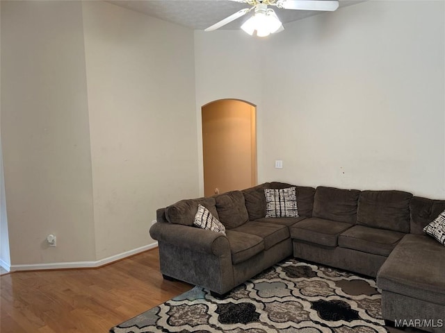 living room featuring wood finished floors, ceiling fan, baseboards, and arched walkways