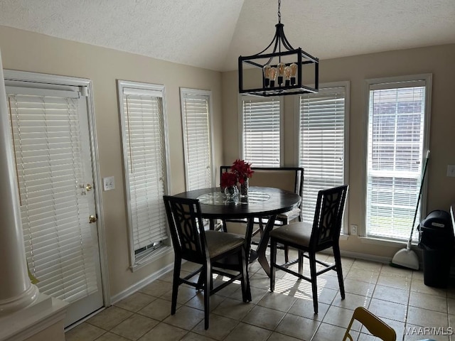 dining area with a chandelier, light tile patterned floors, vaulted ceiling, baseboards, and a textured ceiling