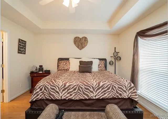 7648 Steele Ridge Dr, Montgomery, AL 36117 - bedroom featuring a tray ceiling, multiple windows, and light wood-style flooring