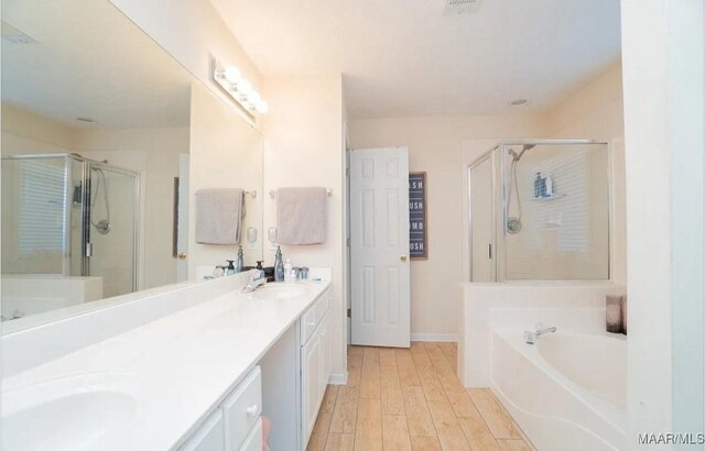 7648 Steele Ridge Dr, Montgomery, AL 36117 - bathroom with a shower stall, a garden tub, double vanity, wood finished floors, and baseboards