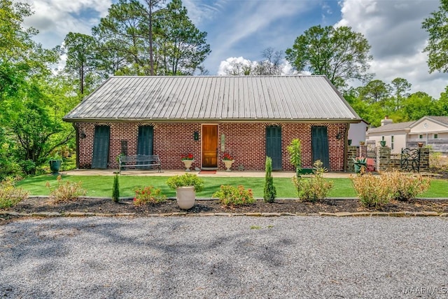 view of front of home featuring metal roof, a front yard, and brick siding