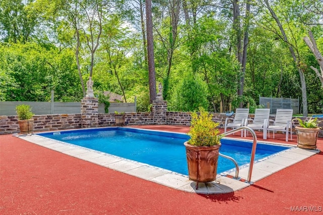 pool with a patio and fence